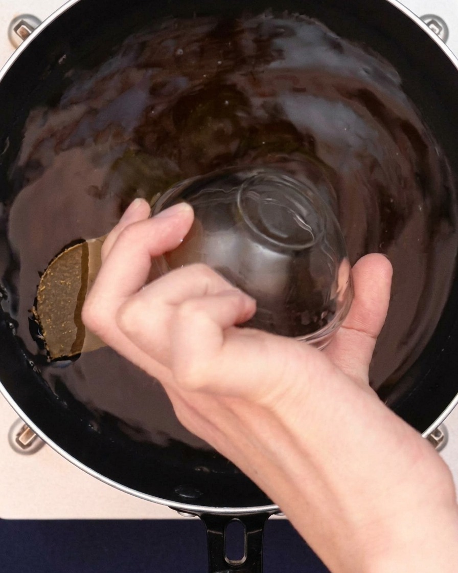 Clear soup bouillon granules being sprinkled into the curry broth.