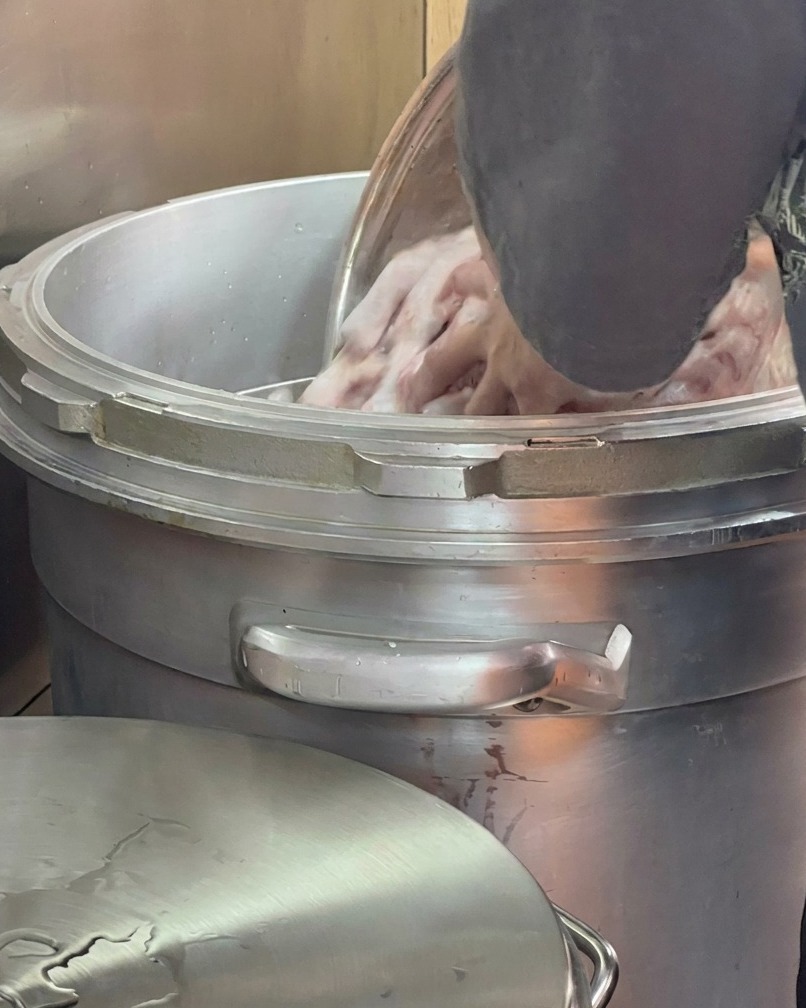 Fresh water being poured over bones inside a large stockpot.