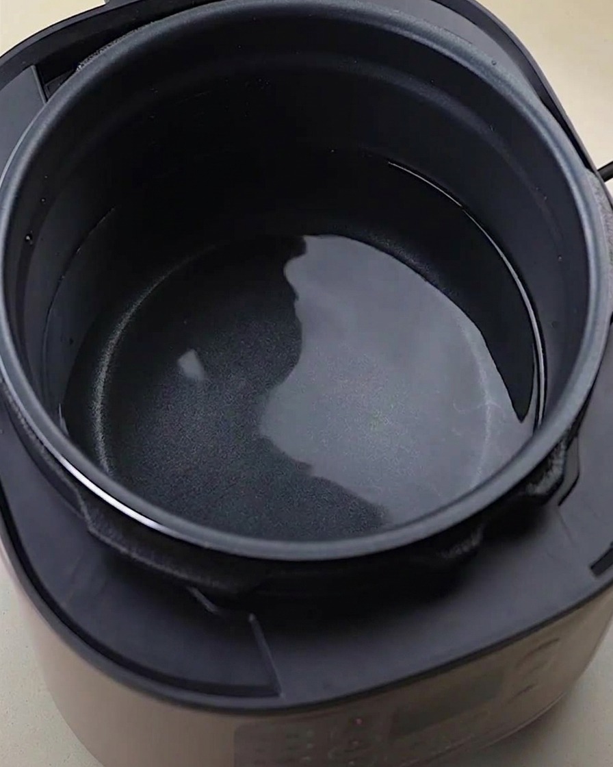 Raw chicken bones wings and feet inside a pressure cooker pot with water