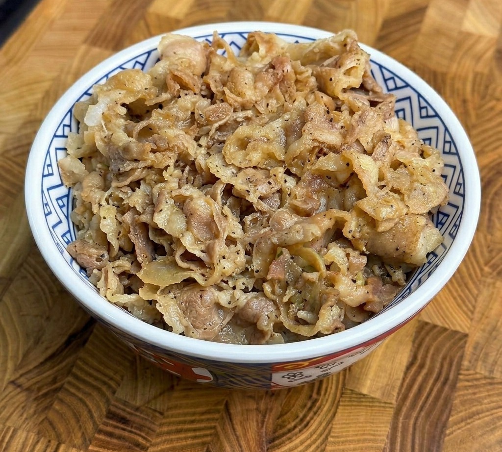 A generous portion of cooked beef and scallions served over fluffy white rice in a patterned ceramic bowl.