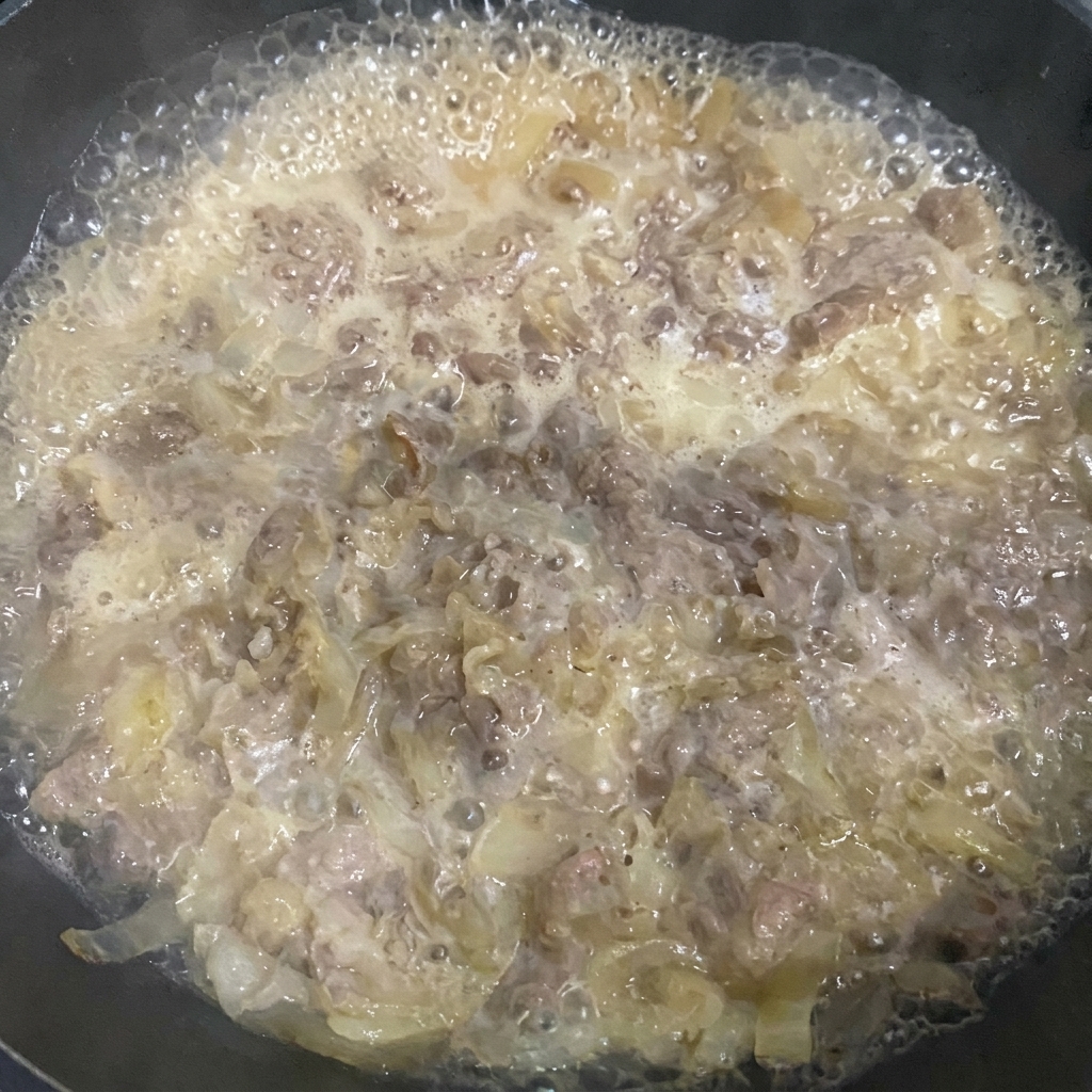 Removing foam from the simmering beef mixture with a spatula.