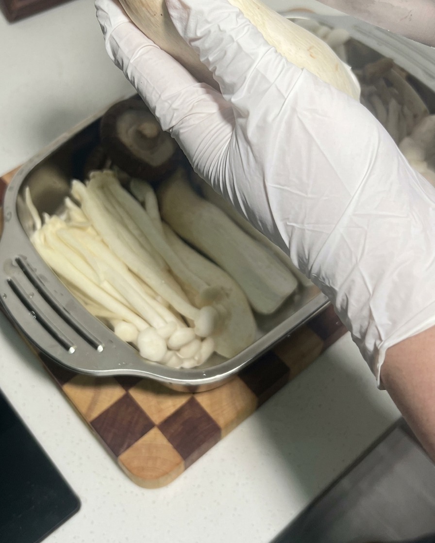 Close-up view of shallow parallel cuts being made into the body of a raw king oyster mushroom.