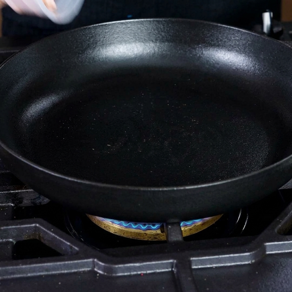Crispy diced bacon pieces frying in a hot cast iron skillet.