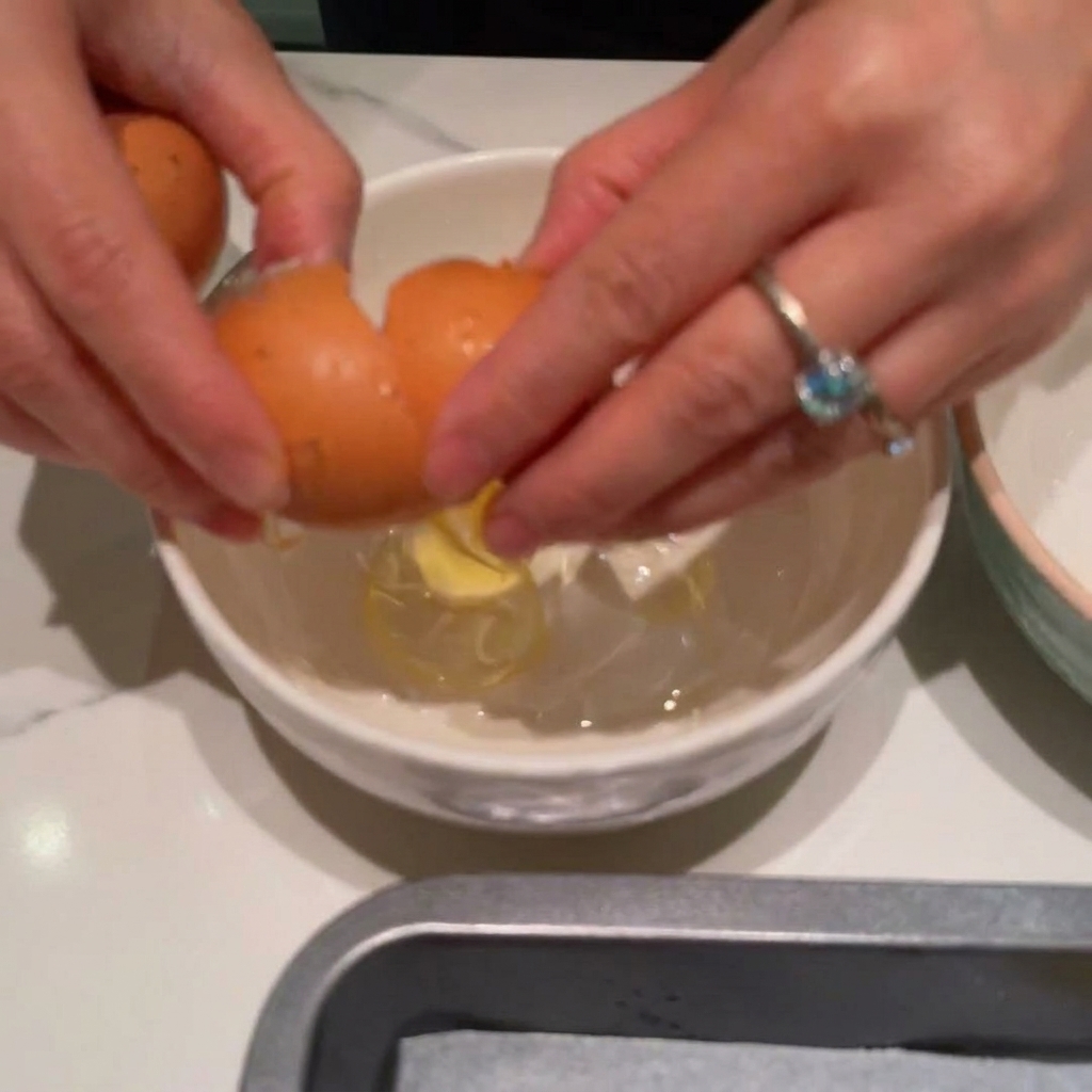 Two eggs being whisked in a white bowl.