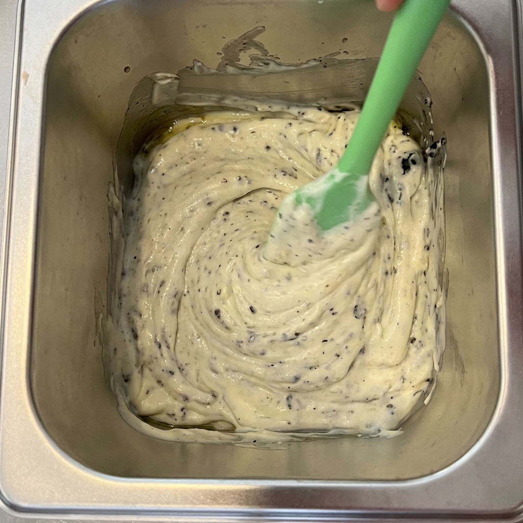 Black truffle, mayonnaise, and olive oil being mixed together in a metal container.