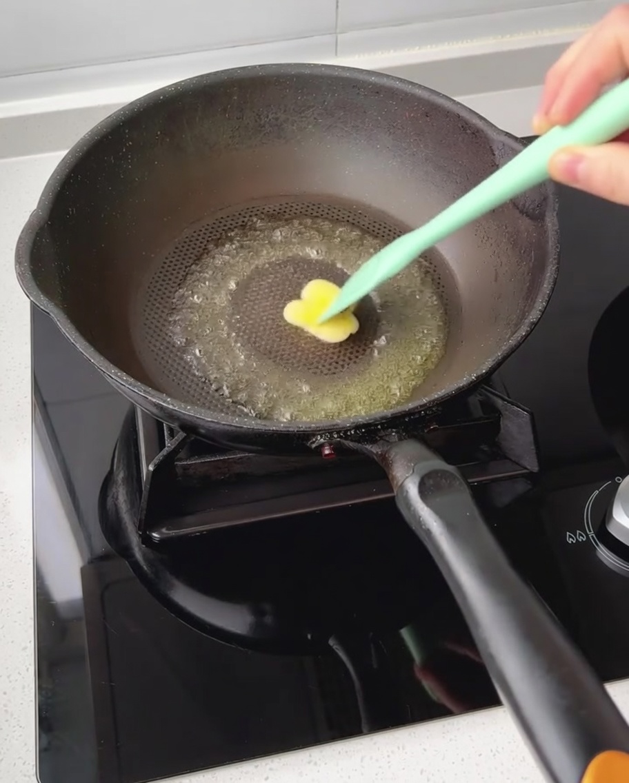A small piece of butter melting in a dark non-stick pan being spread by a spatula.