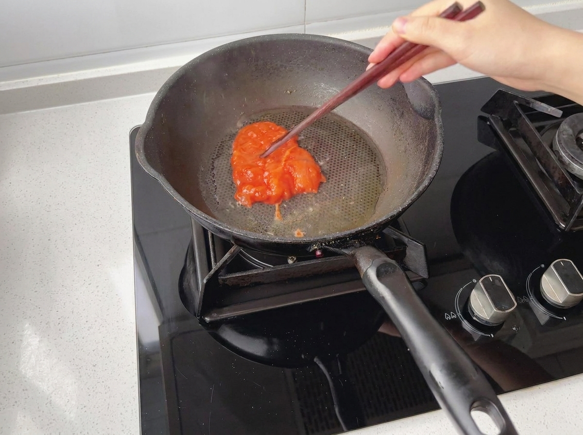 Marinated chicken pieces being placed into a preheated, oiled pan.