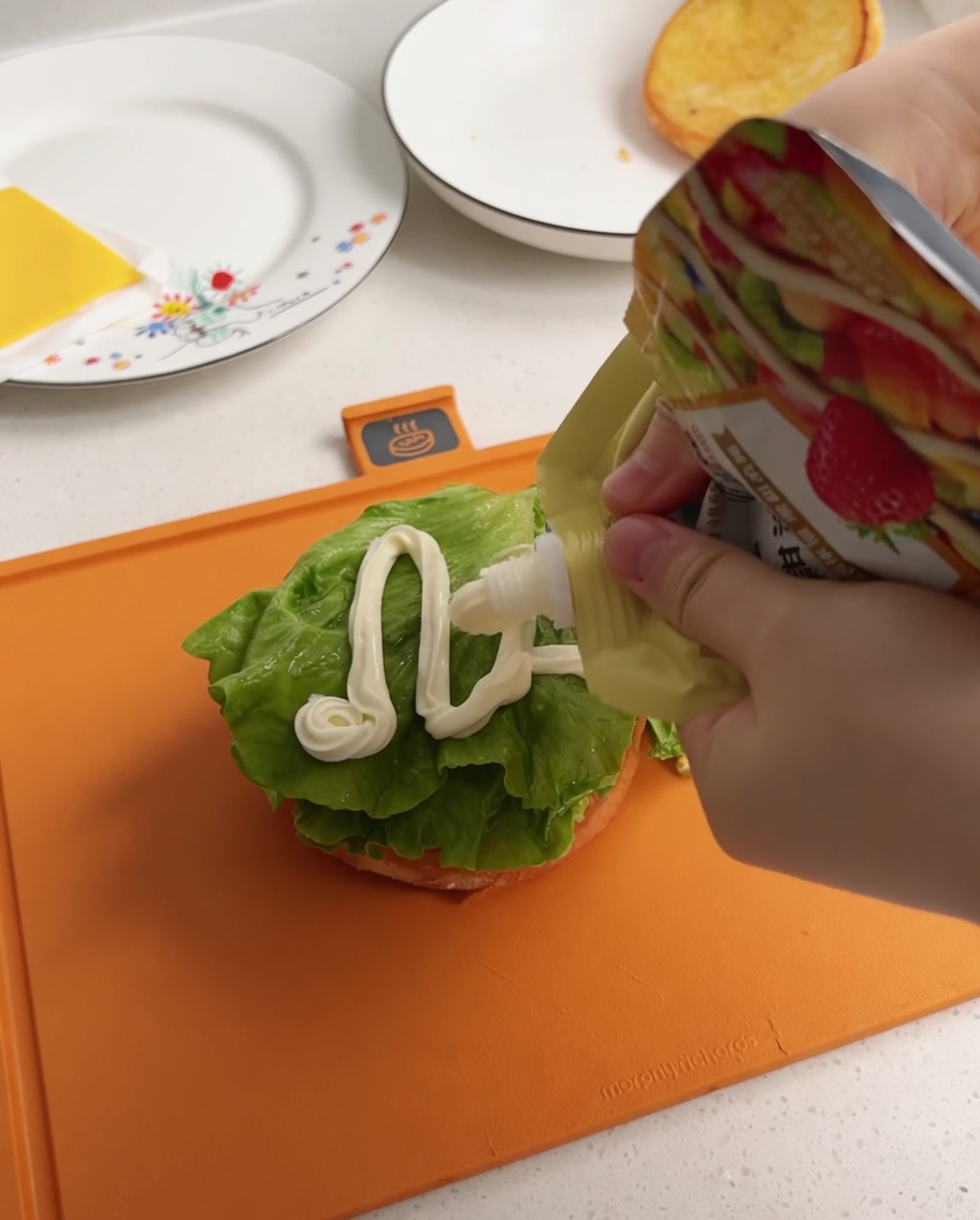 White salad dressing being squeezed from a pouch onto a lettuce leaf.