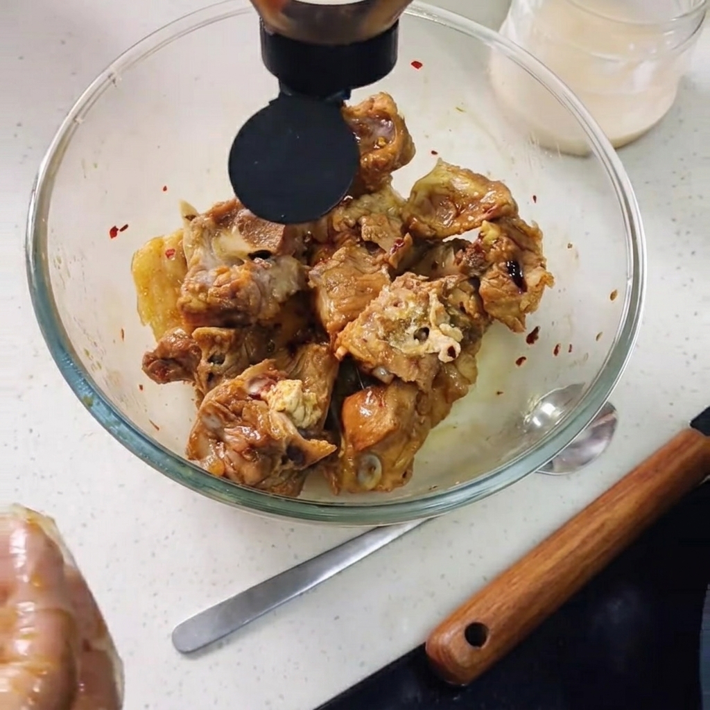 Oyster sauce being squeezed into the bowl over the pork ribs, with lemon slices added.