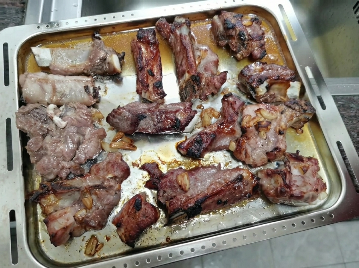 Roasted, caramelized pork ribs resting on a metal baking tray.