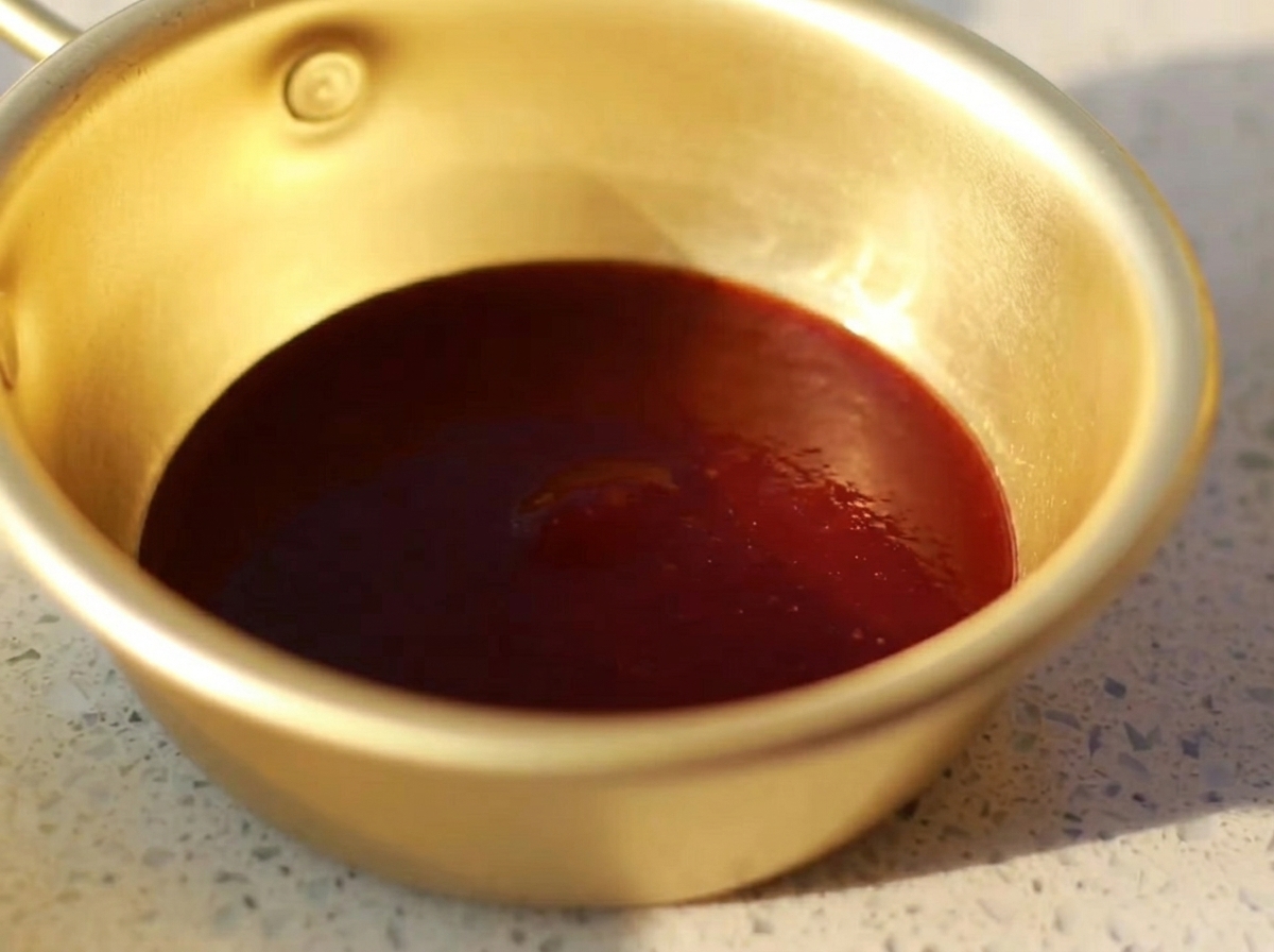 A small metal bowl containing a smooth mixture of barbecue sauce, oyster sauce, mustard, honey, and light soy sauce.