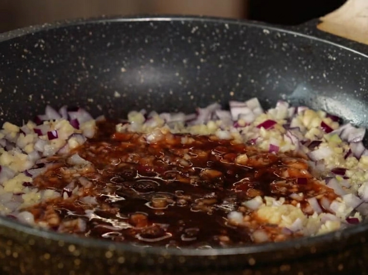 Liquid sauce ingredients and diced apples simmering in a frying pan.