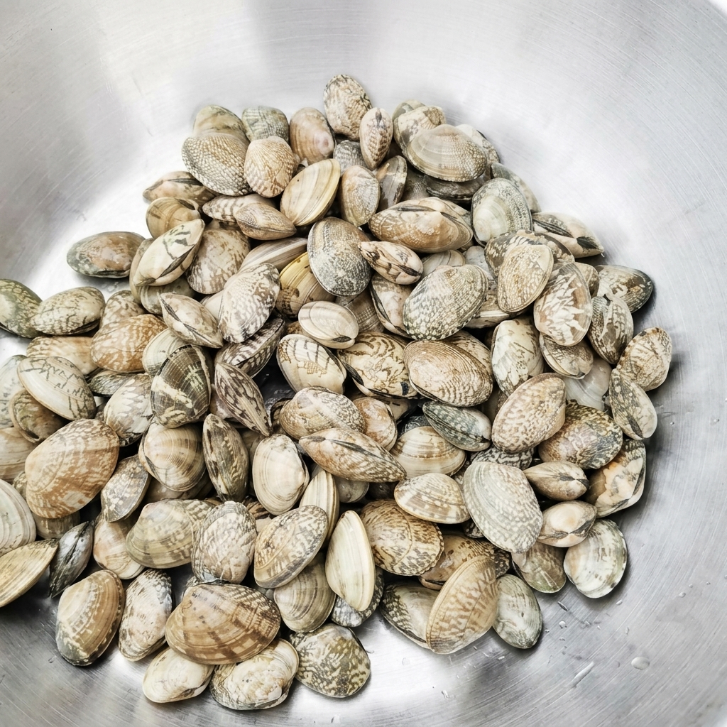 Fresh clams in a metal basin being rinsed with clean water.