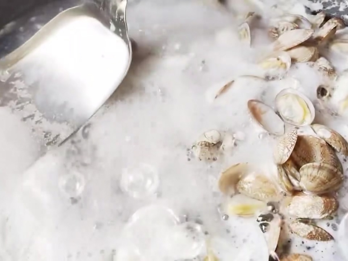 A metal skimmer removing foam from the surface of boiling water.