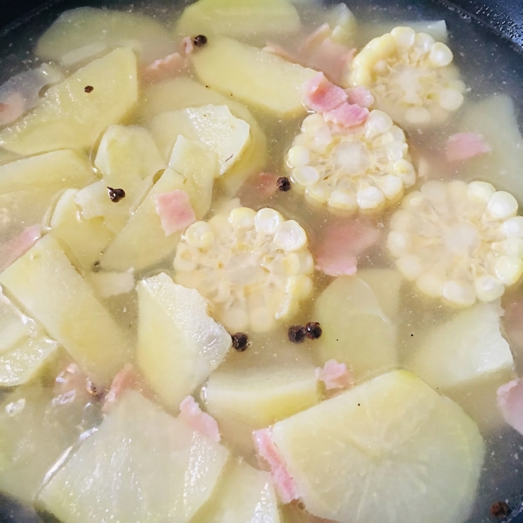 Shelled clam meat being stirred into a simmering pot of corn and bamboo shoot soup.