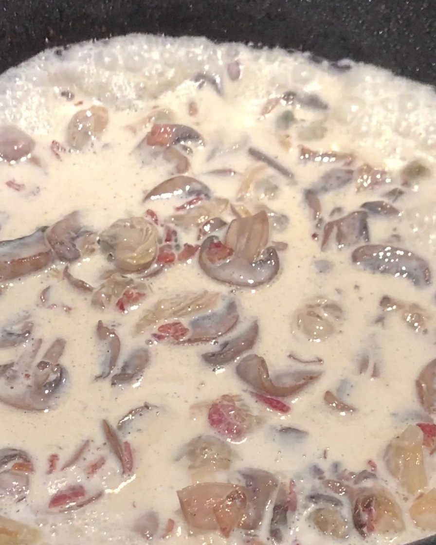 Creamy mushroom soup with potato cubes in a pan.