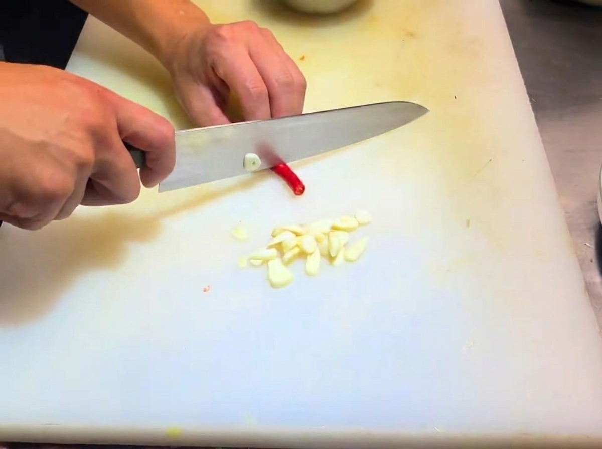 Sliced shallots and chili pepper pieces prepared on a cutting board.