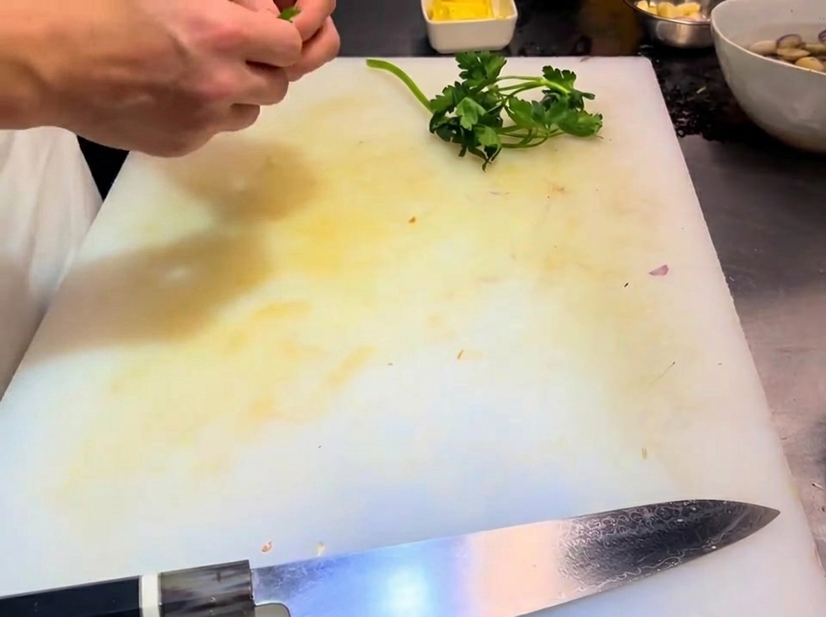 Separated parsley leaves and stems arranged on a cutting board.