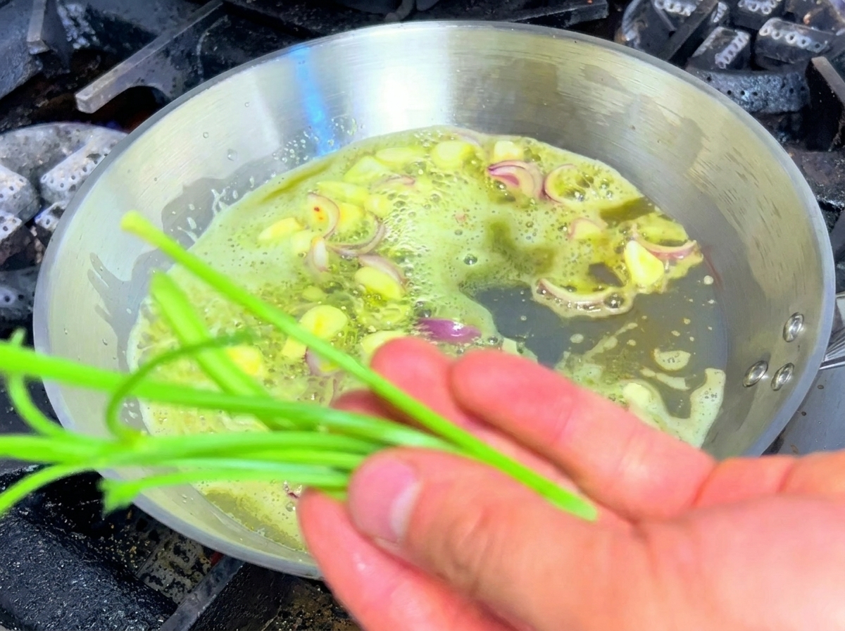 Parsley stems being sautéed alongside garlic and shallots in a pan of butter.