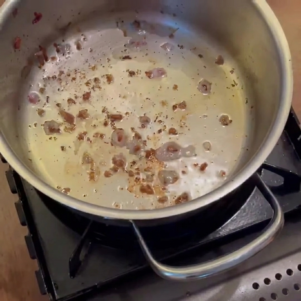 Onions, carrots, and potatoes sautéing in the pot with bacon fat until translucent.