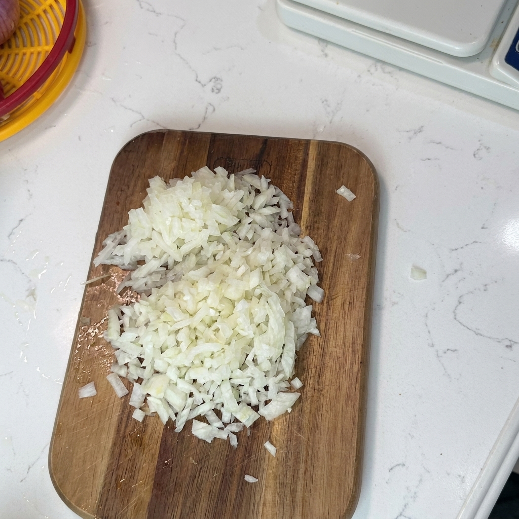 Finely minced celery, onion, and carrots prepared on a wooden cutting board ready for cooking.