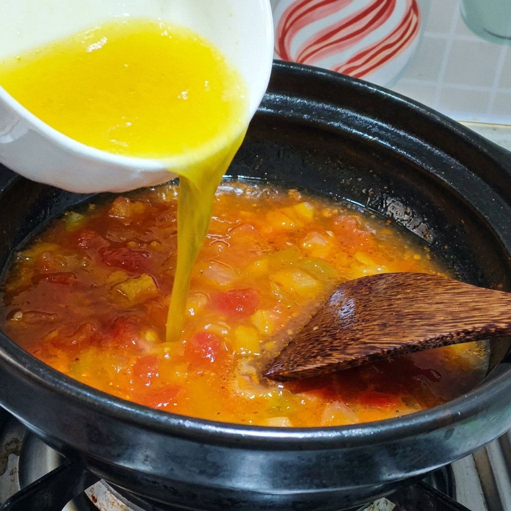 Chicken broth being poured into a pot with sautéed tomatoes.