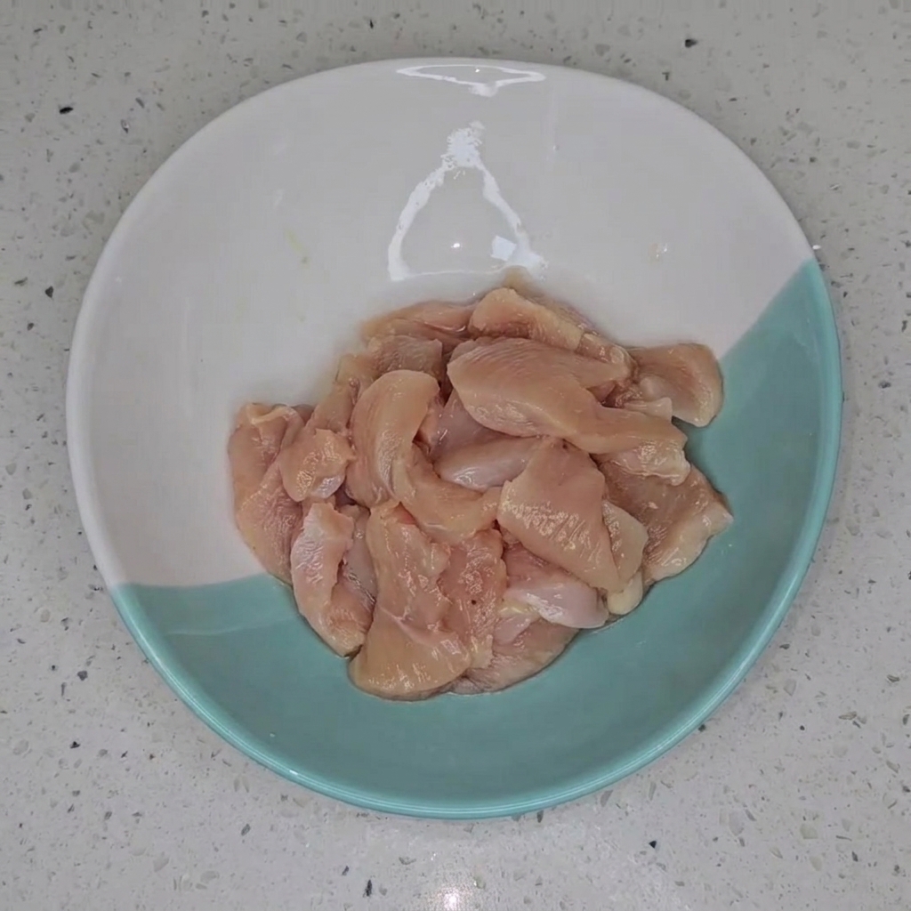 Marinated chicken breast pieces sitting in a two-toned bowl, ready for the next cooking stage.