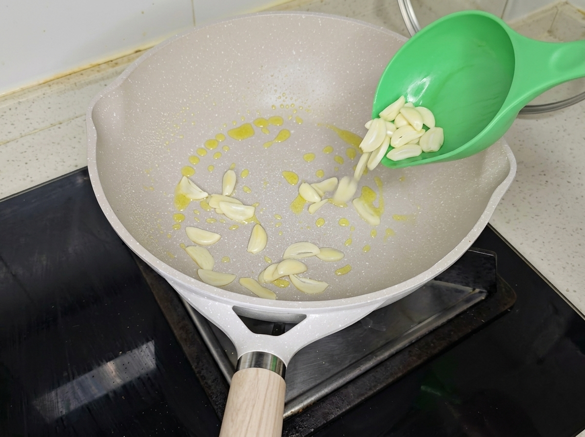 Garlic slices and green scallions sizzling in a pan with olive oil.