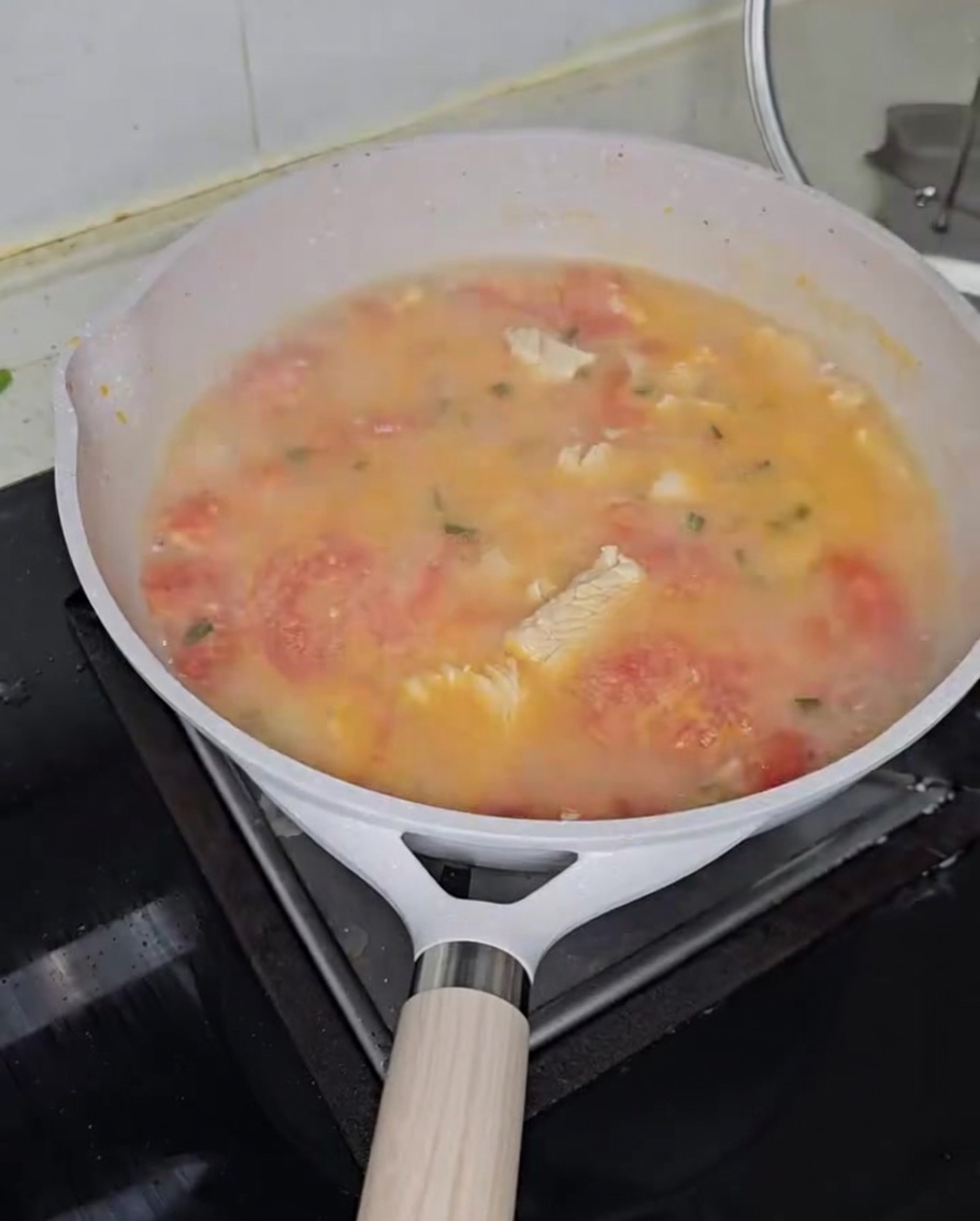 Buckwheat dough drops being dropped into a simmering tomato chicken soup.
