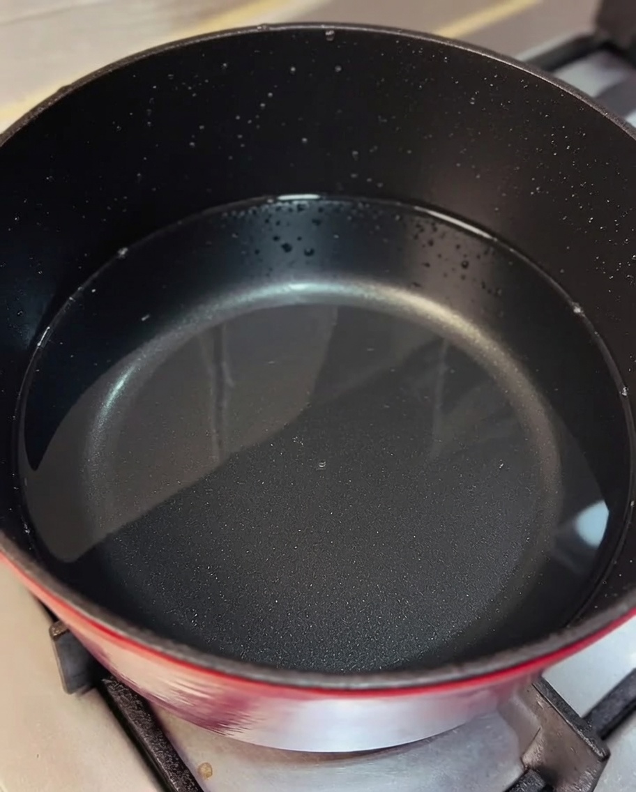 Shredded chicken being stirred into a pot of simmering broth.