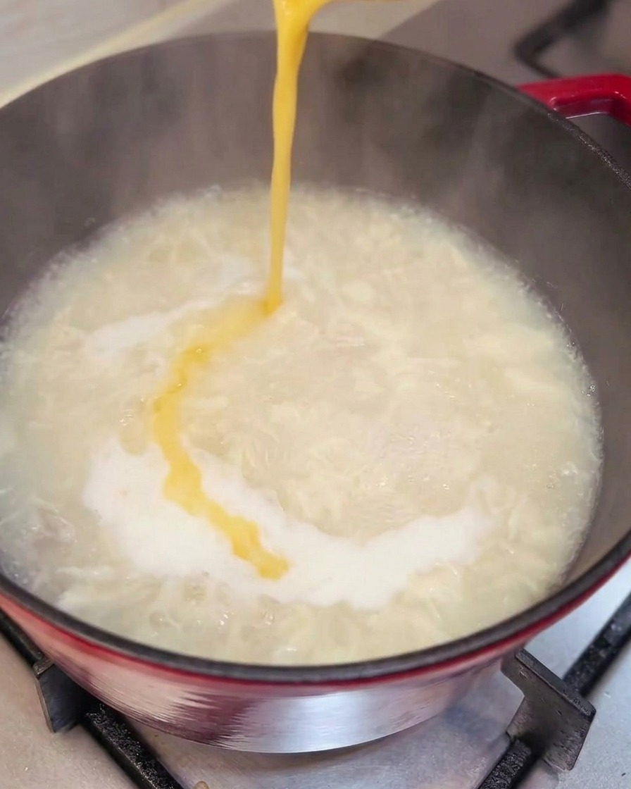 Egg being poured into soup, forming ribbons.