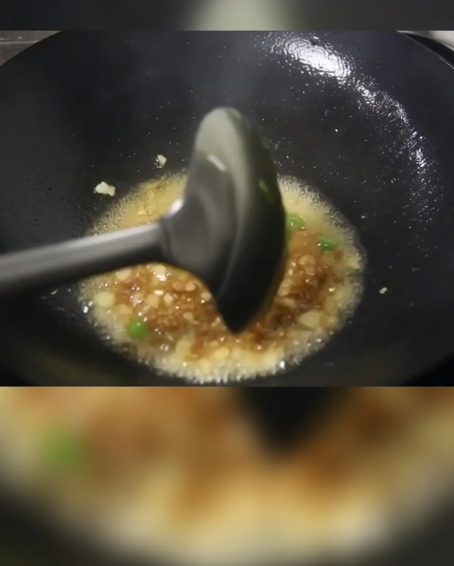 Green onions, diced meat, and potato cubes cooking in a hot wok with oil.