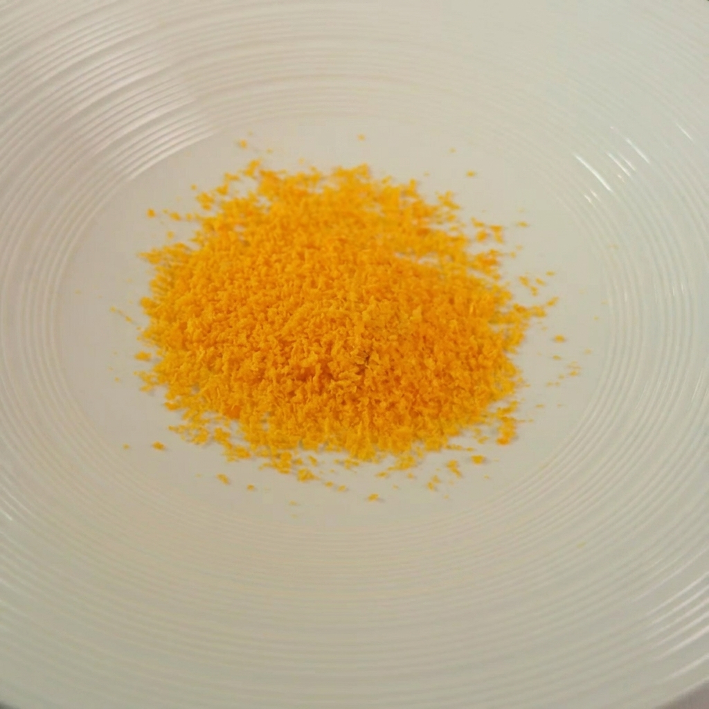 A bowl containing a golden mixture of breadcrumbs, herbs, and grated cheese.