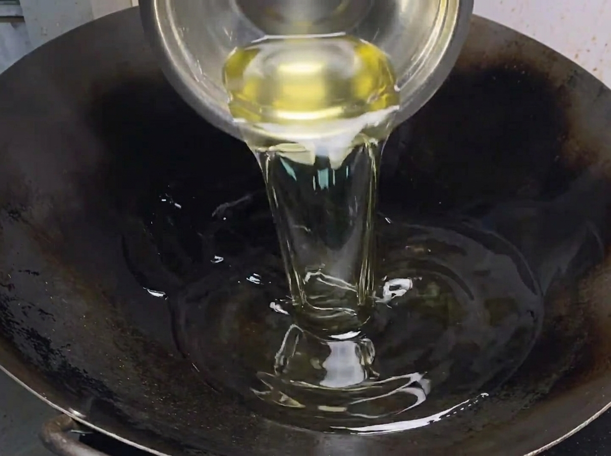 Pixian bean paste being incorporated into the oil and aromatics, turning the mixture into a rich red color.