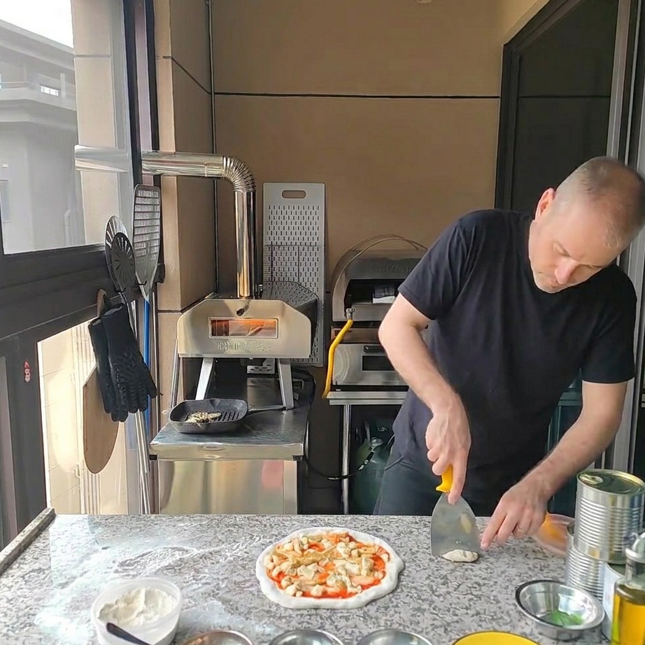 Grilled chicken pieces being placed on top of the artichoke and cheese-covered pizza.