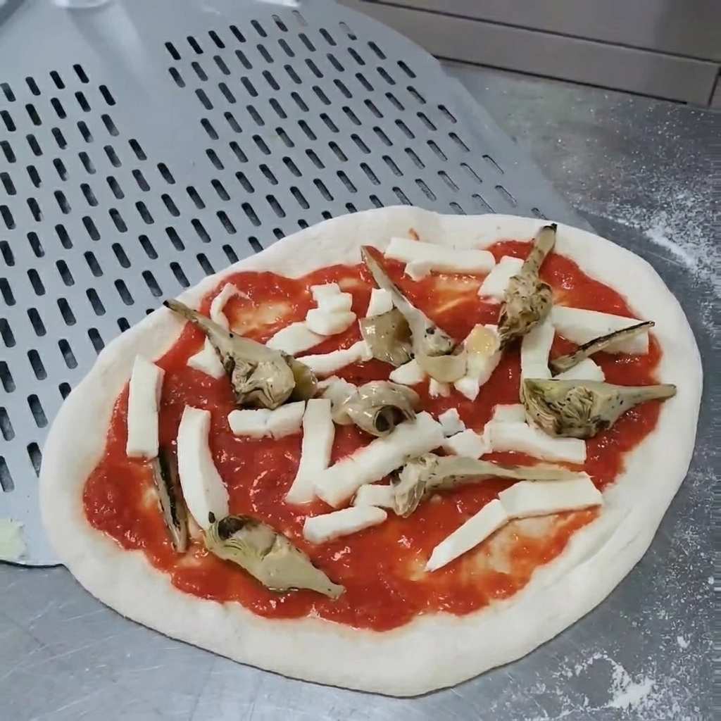 Hands adjusting the position of grilled artichokes on the raw pizza to ensure even coverage.