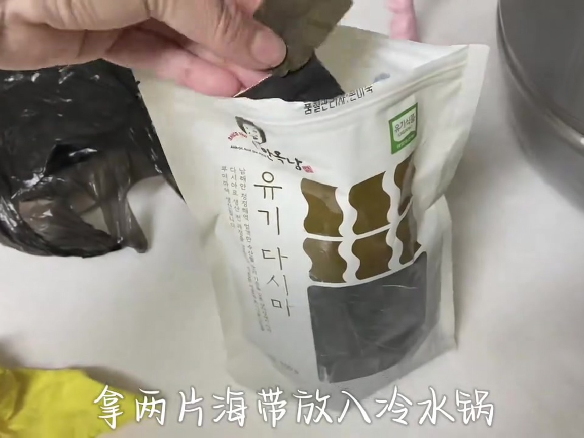 Two pieces of dark dried kelp held by hand against a clear package background.