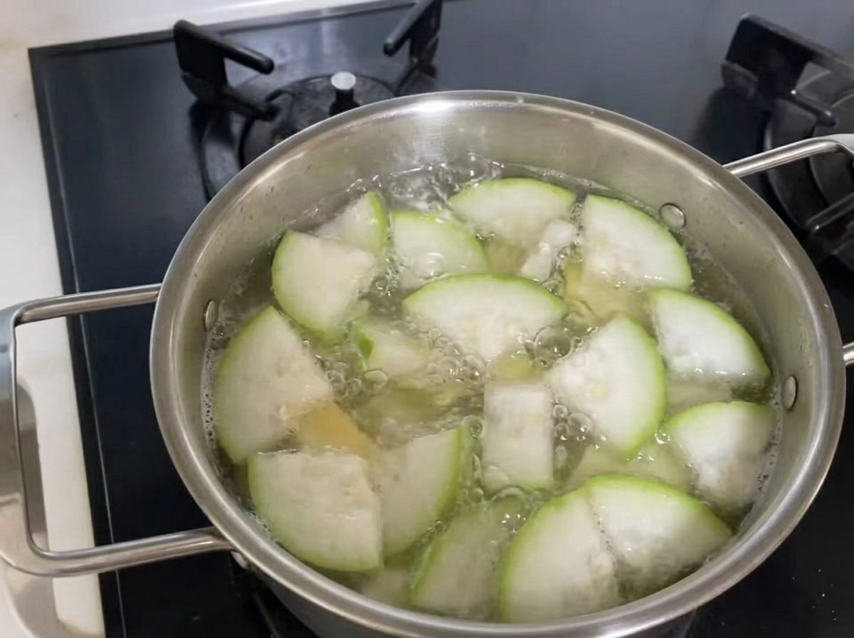 Metal tongs lifting a portion of noodles, zucchini, and clams from the boiling soup pot.