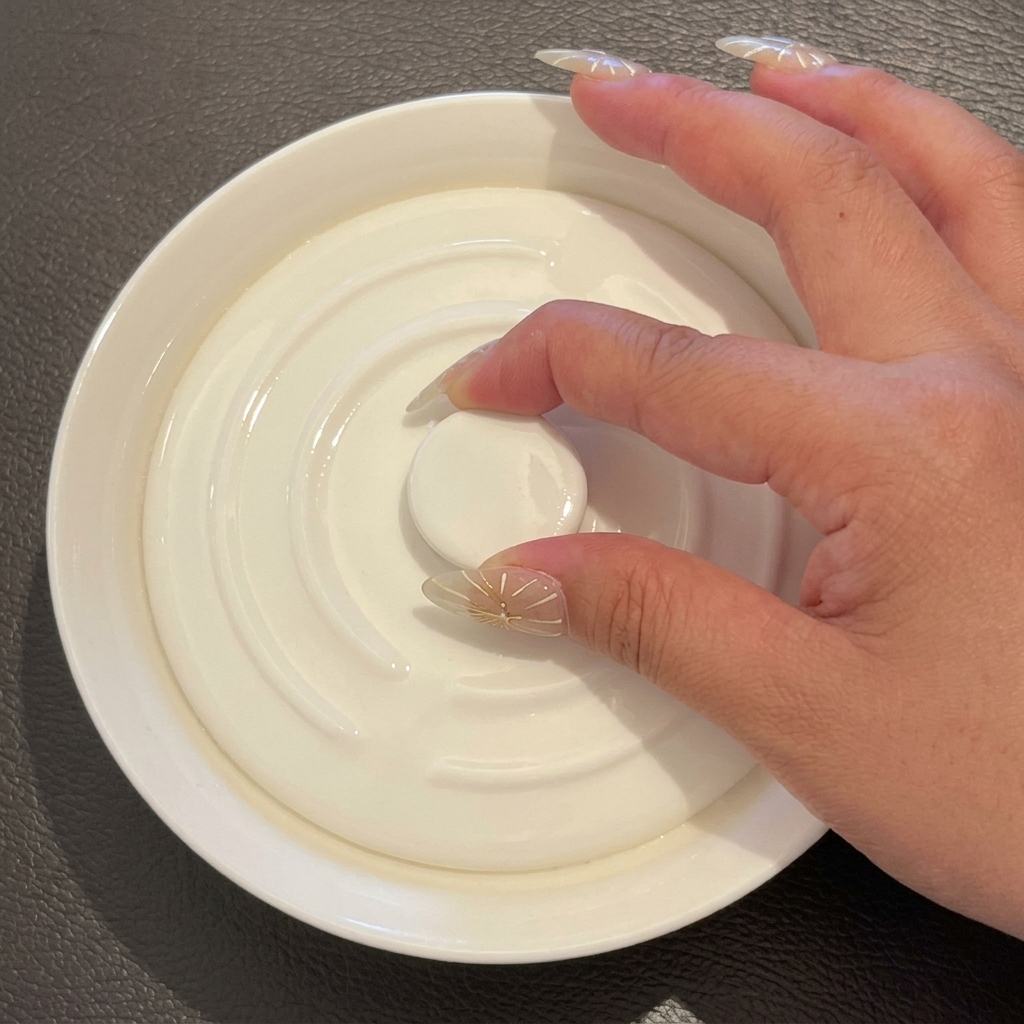 A hand placing a white ceramic lid onto the bowl containing the rice and water.