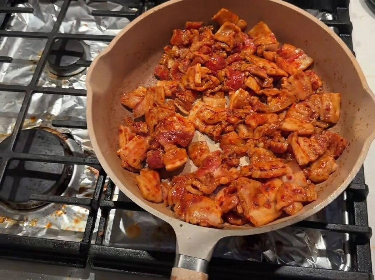 Searing pork belly in a pan with cooking wine being added along the inner rim.