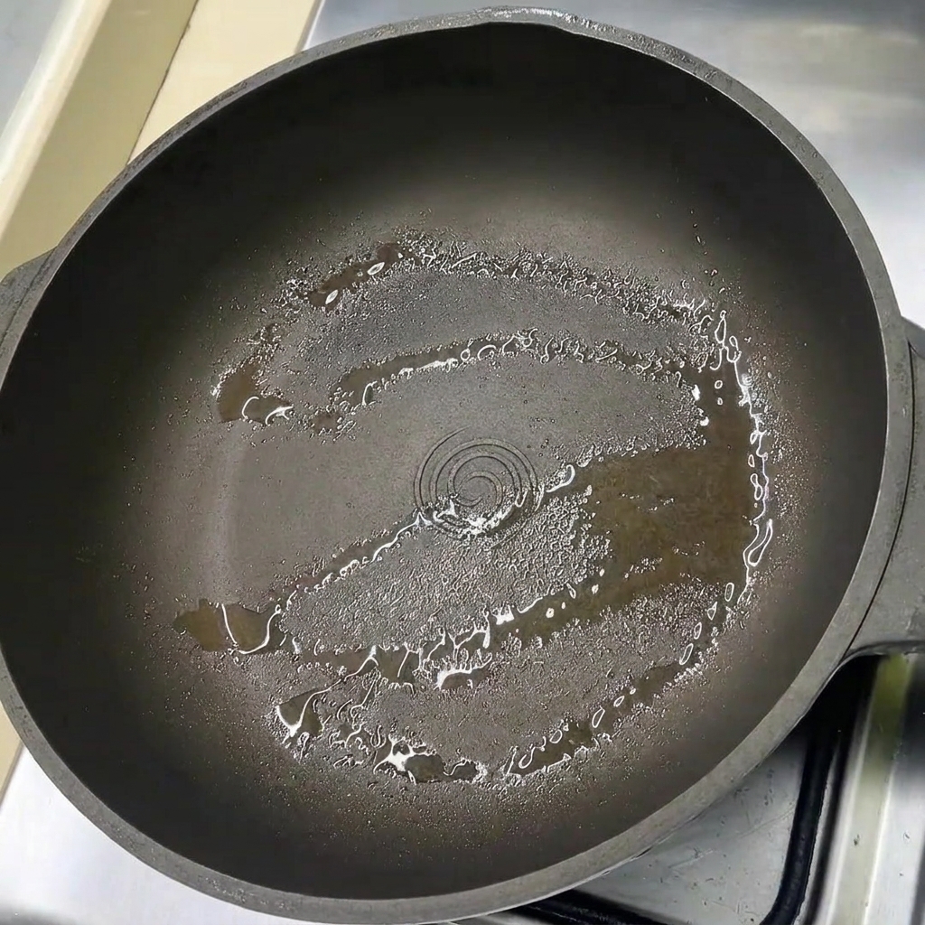 Slices of pork belly laid out in a lightly oiled pan.