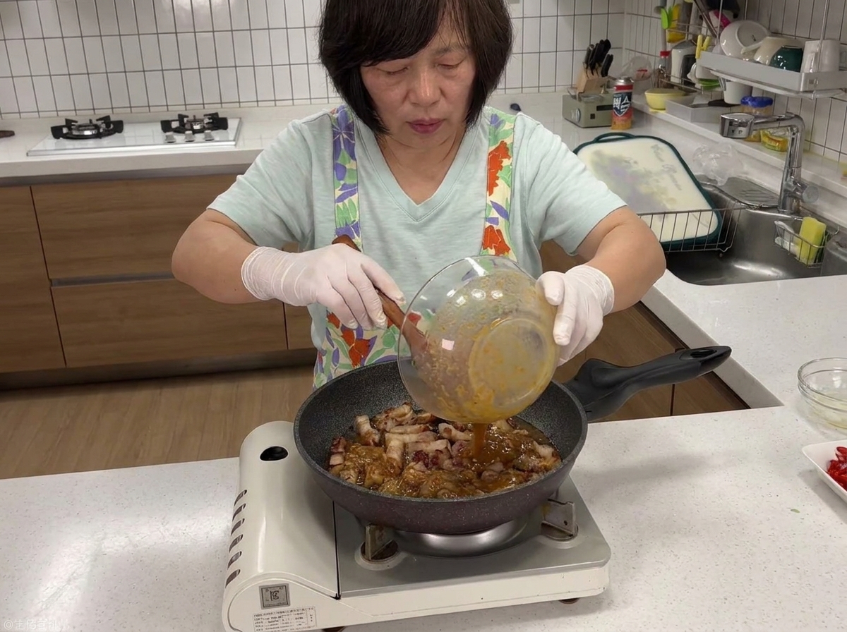 Dark soybean paste sauce being poured from a bowl into a pan containing browned pork belly.