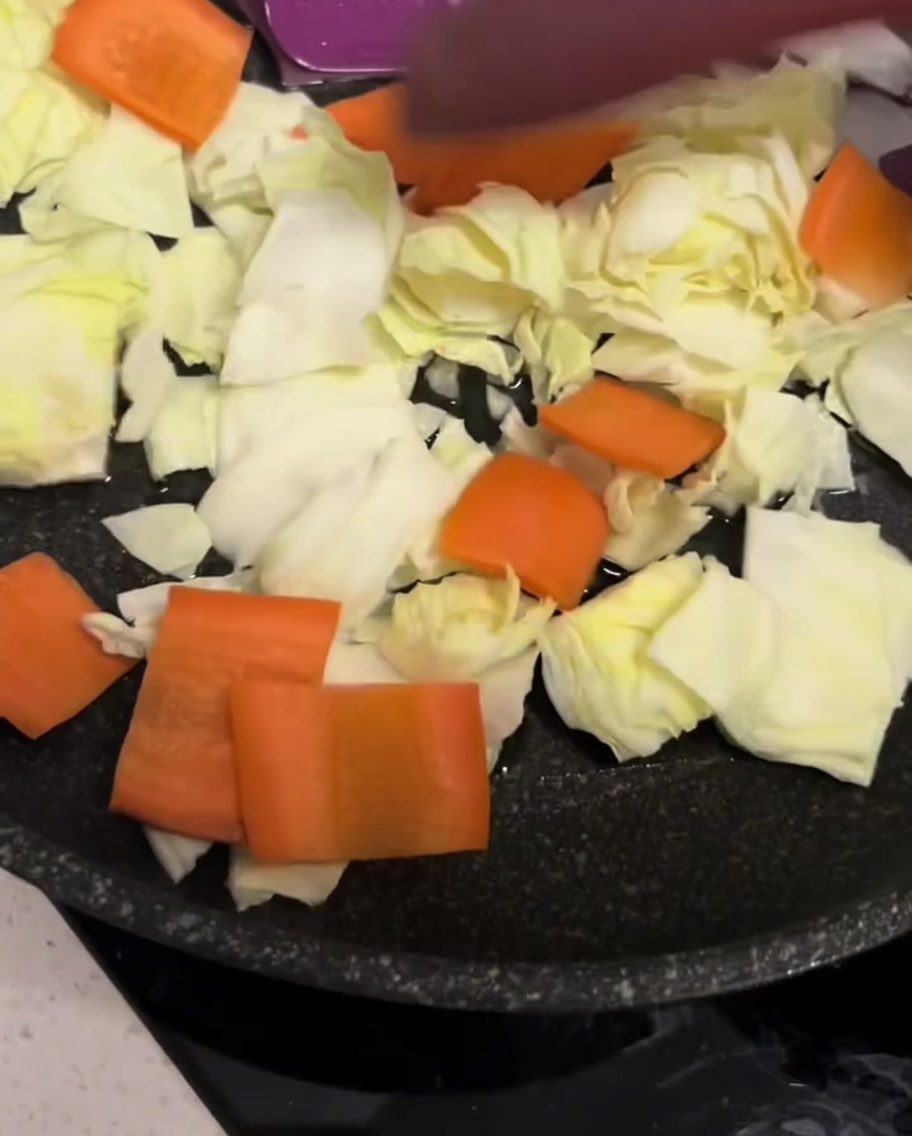 An assortment of chopped vegetables spread out across the surface of a black skillet.