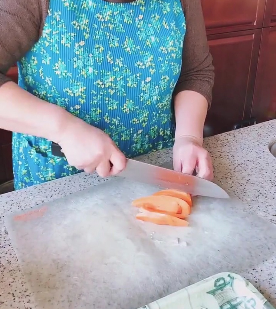 King oyster mushrooms being sliced into pieces on a kitchen cutting board.