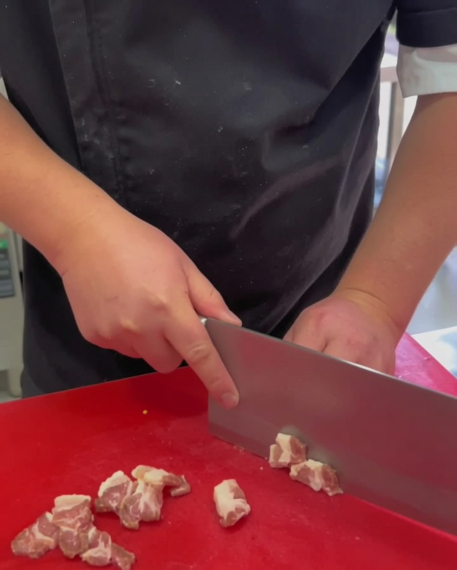 Thin slices of raw pork belly arranged on a red cutting board.