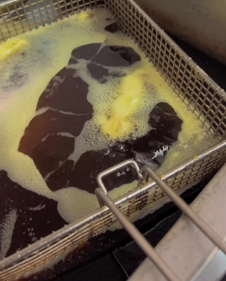 Green beans frying in hot oil in a deep fryer.