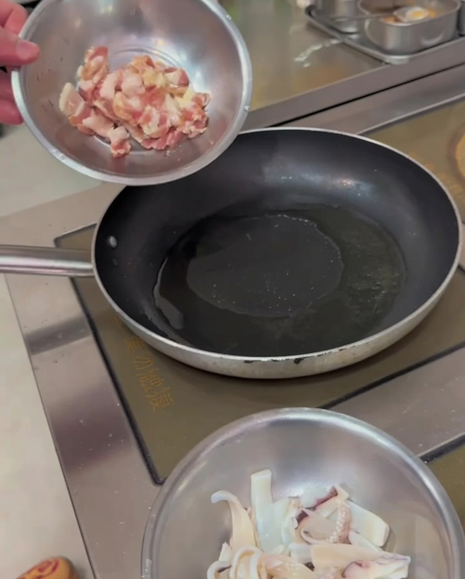 Pork belly strips sizzling in a hot pan, showing golden-brown edges.