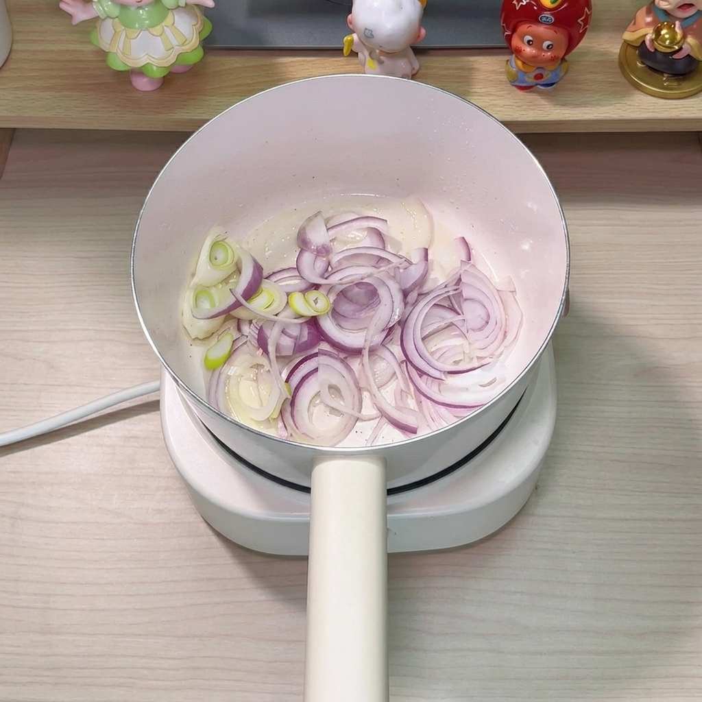 Onion slices and green onion pieces sautéing in the pot, glistening with tuna oil.