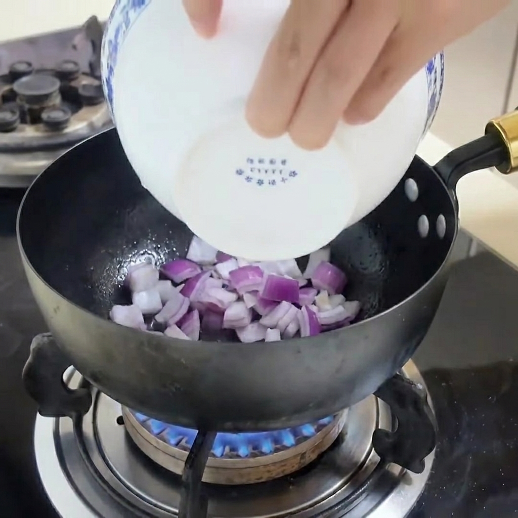 Sautéed red onion slices in a pan, glistening with cooking spray.