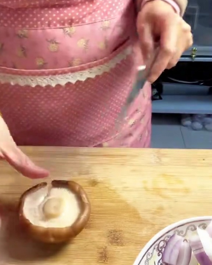Fresh shiitake mushrooms sliced into uniform thin strips on a wooden cutting board.